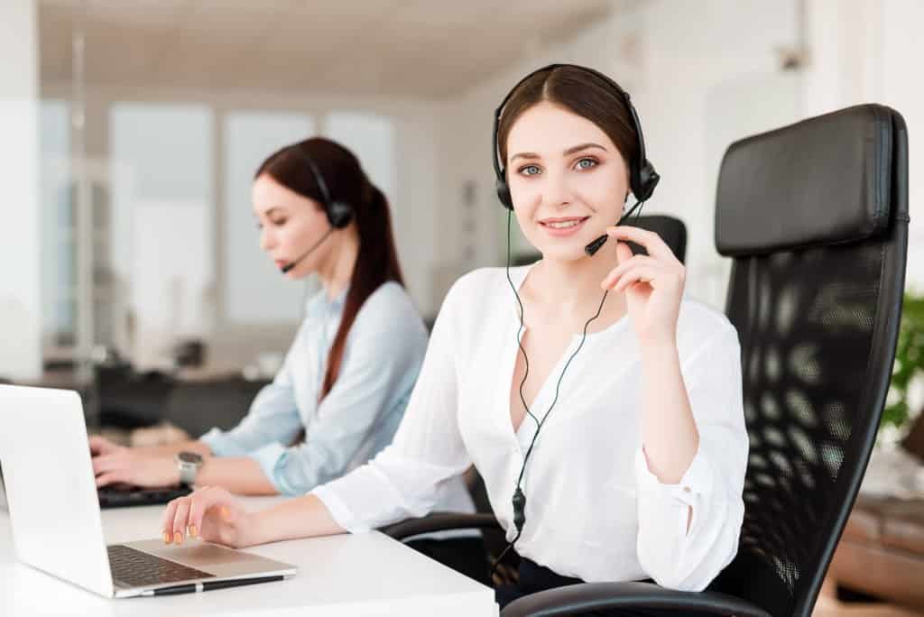 Two women providing computer support in an office with headsets.
