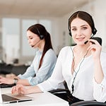 Two women providing computer support in an office with headsets.