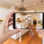 A person using a camera smartphone to capture an image of a kitchen.