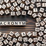 The word acronym spelled out in wooden blocks representing computer tech.