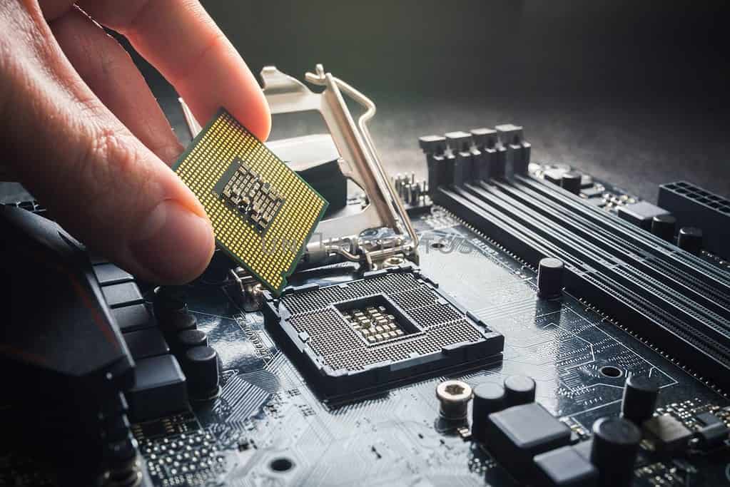 A hand is holding a CPU on top of a motherboard for computer tech support in Naples, Florida.