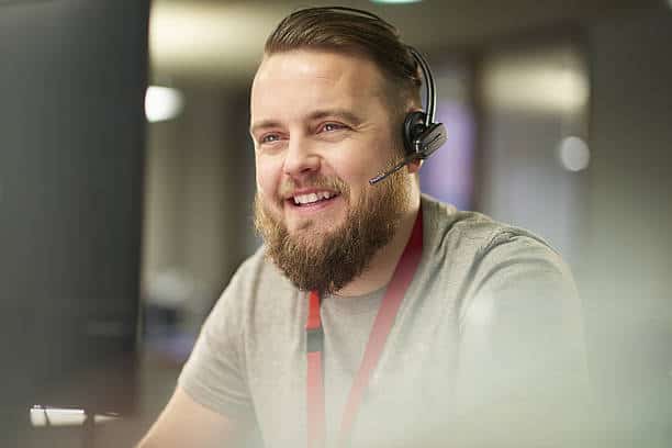 A bearded man providing IT support in Naples, Florida, seated at a computer with a headset.