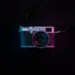 A camera on a black background with neon lights.